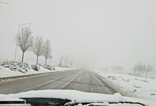 Foggy, snowy road from car window